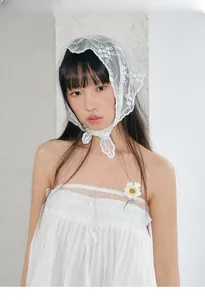 Detail of white lace triangle headscarf with floral embroidery and wavy scalloped edges