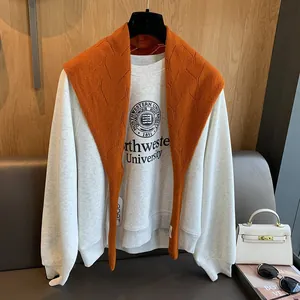 Détail d'un châle en laine orange à motif de losanges sur un sweat-shirt gris collégial