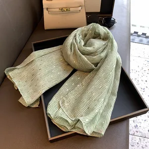 Detail of light green striped scarf with gold foil accents on a display tray