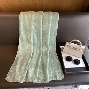 Detail of mint green scarf with vertical stripes and golden foil print on leather