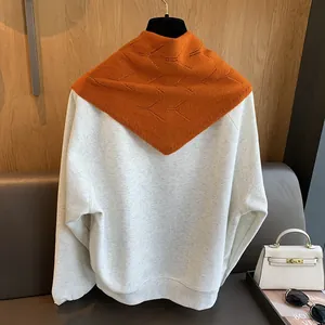 Détail du châle en laine à losanges sur un sweat-shirt beige aux textures douces