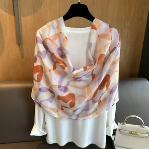 Detailed texture of lightweight orange and purple abstract print scarf on a white shirt