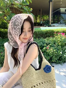 Detailed view of pink floral lace scarf styled with a straw tote bag for a resort look