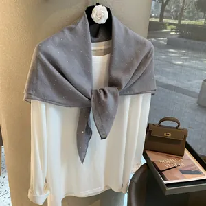 Détail d'une écharpe en lin gris avec strass scintillants sur un haut blanc