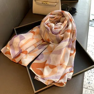 Close-up of lightweight printed scarf styled with elegant leather bag and sunglasses