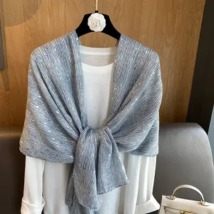 Detail of blue and white striped lightweight scarf with gold sequins over a white shirt