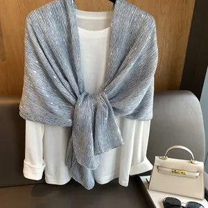 Detail of blue and white striped scarf with gold foil dots styled on white casual outfit