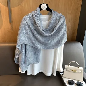 Detail of blue and white striped cotton scarf with frayed edges on a wooden hanger