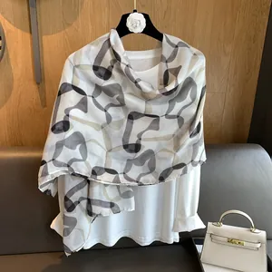 Detailed view of lightweight printed scarf with geometric patterns on a white garment