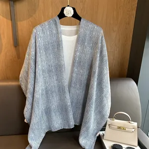 Detail view of a blue and white striped cotton shawl over a white t-shirt on a hanger
