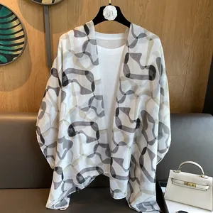 Detail of sheer lightweight printed shawl over white top with abstract wave pattern