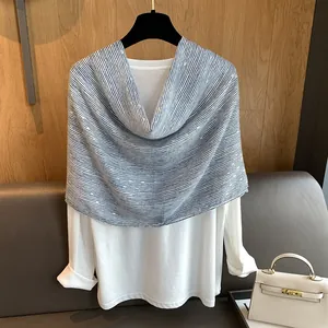 Detailed view of white cotton top styled with a striped scarf and sequin accents