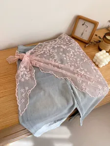Detailed close-up of pink lace ribbon with floral embroidery tied on denim fabric