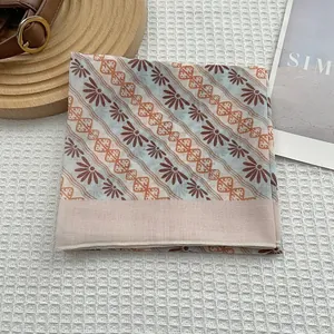 Détail d'un foulard en soie à fleurs françaises avec motif éventail marron et bord orange