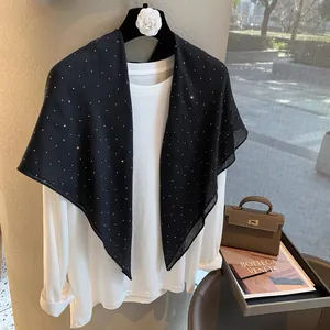 Détail d'un châle en lin noir fin orné de délicats motifs d'étoiles en strass brillants