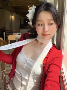 Detailed view of elegant white floral lace scarf paired with a red knit cardigan