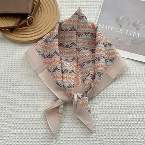 Détail d'un foulard carré à fleurs noué sur tissu blanc avec motifs bohémiens