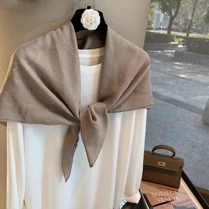 Détail d'une écharpe en coton et lin marron avec strass brillants et décor floral