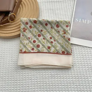 Détail d'un foulard en soie à fleurs avec imprimé baies rouges et bords roulés