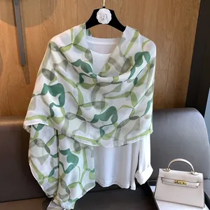 Detailed view of the lightweight floral print scarf with green and grey abstract patterns