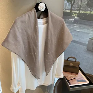 Détail d'une écharpe en coton lin marron avec strass scintillants sur un cintre chic