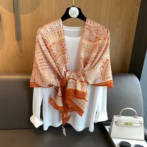 Detail of ethnic floral print silk scarf in orange and white with a smooth texture
