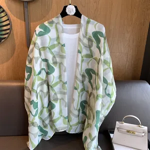 Detail of a lightweight green floral printed scarf draped on a white shirt
