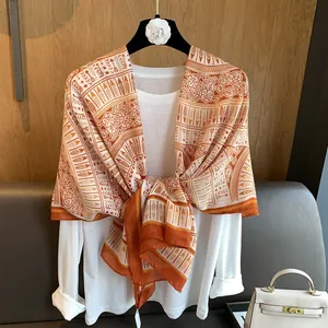 Close-up of bohemian printed scarf in orange and tan hanging on a designer hanger