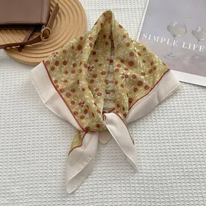 Détail d'un foulard carré à fleurs françaises noué en boucle avec motifs de baies