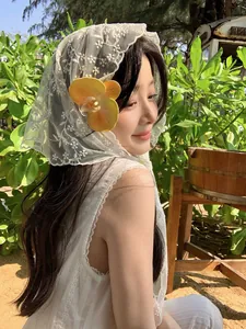 Close-up of white lace triangular scarf with delicate floral embroidery on fabric