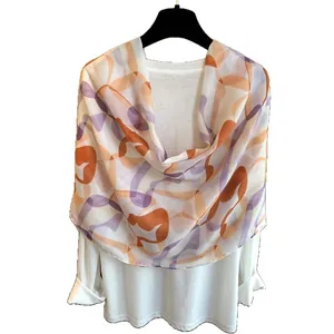 Artistic abstract print shawl in orange and pink tones draped on a white shirt