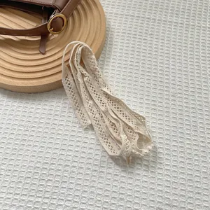 Detailed texture of off-white lace ribbon with floral pattern on a leather bag