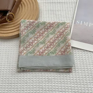 Mise à plat d'un foulard en soie à fleurs vintage avec motifs verts et bordure grise