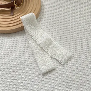 Detailed close-up of white floral lace scarf ribbon with intricate hollow-out embroidery