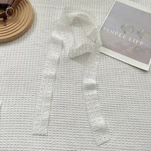 Detailed macro view of white floral lace ribbon with intricate hollowed patterns