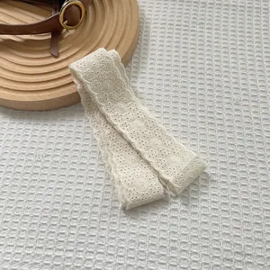 Close-up of cream lace scarf with delicate floral embroidery and scalloped edges