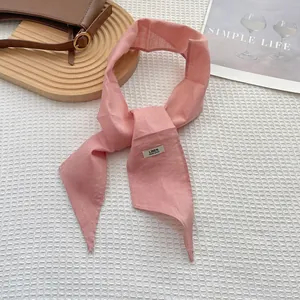 Detail of pink linen skinny scarf with handmade tag on white waffle texture fabric