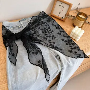 Detail of elegant black floral lace embroidery styled over denim pants for a layered look