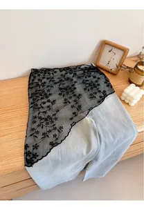 Detailed close-up of light blue jeans featuring black floral lace overlay and embroidery