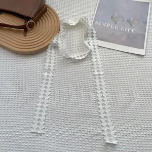 Dettaglio della sciarpa in pizzo bianco con trama geometrica e finitura traforata