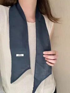 Detailed view of dark blue linen neck scarf with diagonal cut ends and white woven label