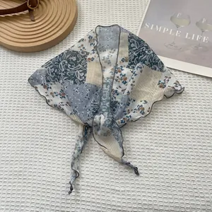 Detail van een chiffon sjaal met paisley-print en elegante ruisranden op houten standaard