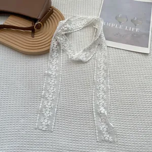 Dettaglio della sciarpa in pizzo bianco con ricami floreali su tessuto mesh