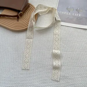 Dettaglio della sciarpa in pizzo bianco con ricamo floreale e bordi traforati decorativi