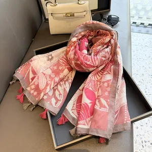 Détail d'une écharpe fleurie rose légère avec glands à franges et motifs floraux élégants