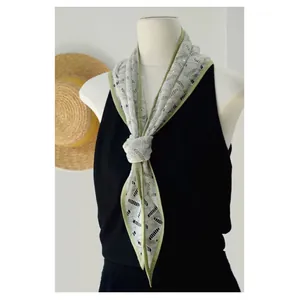 Detailed view of grey lace hollow tie-dye scarf with green edges on a mannequin
