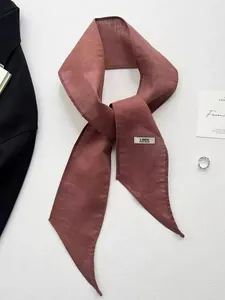 Detail of a dark red handmade linen scarf with a label on a clean white background