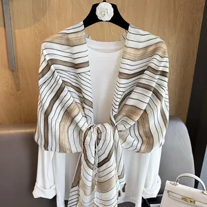 Elegant striped linen shawl in brown and black tones styled with a white handbag
