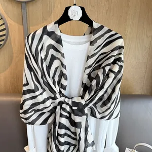 Klassischer Zebra-Print Schal in Schwarz-Weiß, gestylt auf einem weißen Oberteil mit Holzdekor