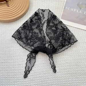 Detalle del pañuelo triangular de encaje negro con bordado floral y bordes ondulados